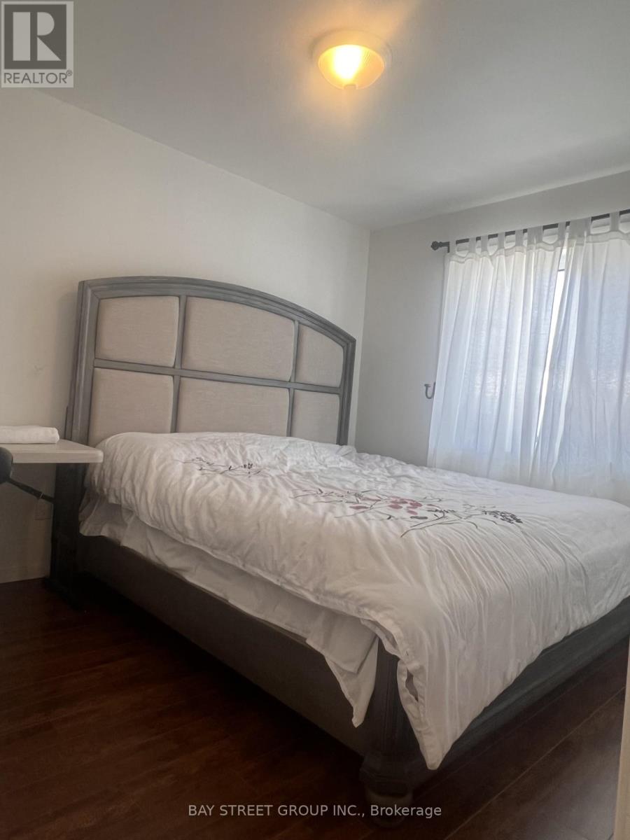 A bedroom with a large bed and a window with curtains.