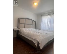 A bedroom with a large bed and a window with curtains.