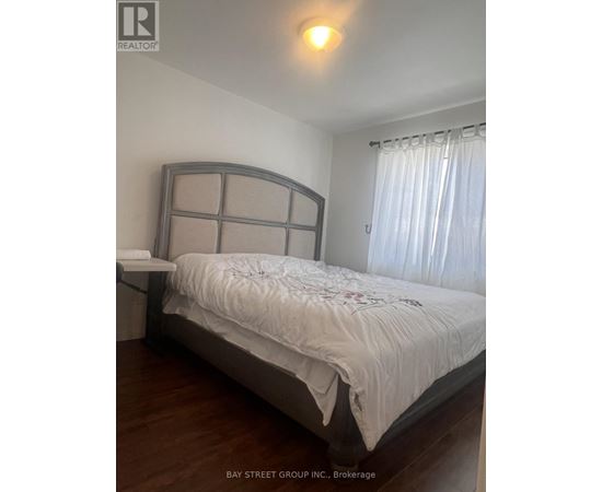 A bedroom with a large bed and a window with curtains.
