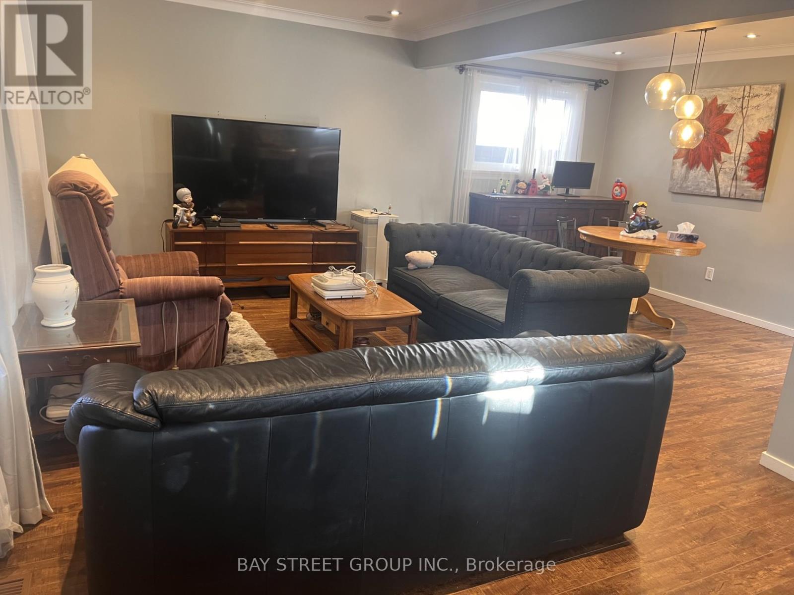 A living room with a black leather couch and a flat screen TV.