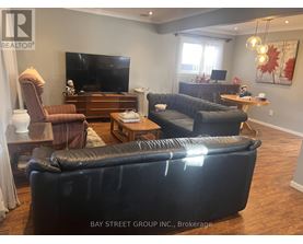 A living room with a black leather couch and a flat screen TV.