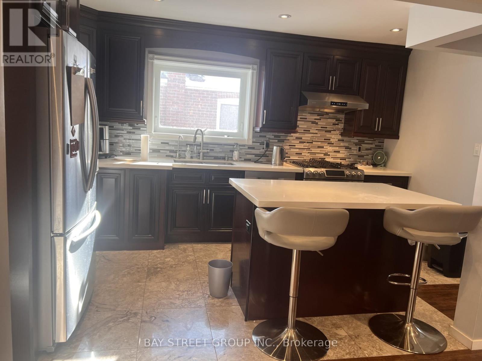 A modern kitchen with dark wood cabinets and a stainless steel refrigerator.