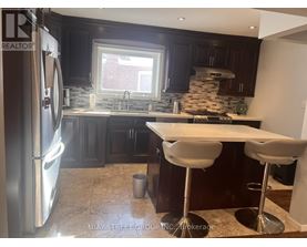 A modern kitchen with dark wood cabinets and a stainless steel refrigerator.