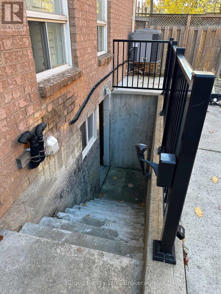 A stairway with a black railing and a brick wall.