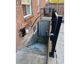 A stairway with a black railing and a brick wall.