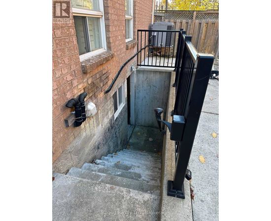 A stairway with a black railing and a brick wall.