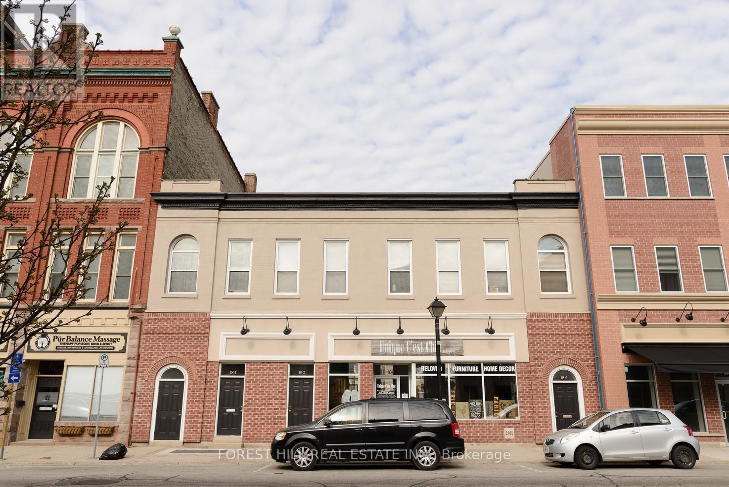 A car is parked in front of a building with a sign that says "Forever Home.".