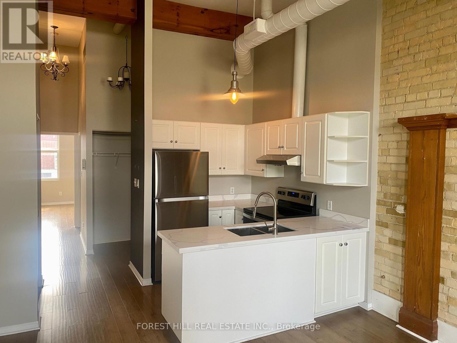 A kitchen with white cabinets and a brick wall.