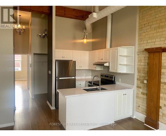 A kitchen with white cabinets and a brick wall.