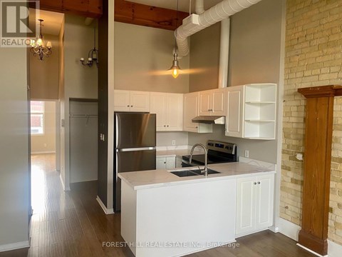 A kitchen with white cabinets and a brick wall.