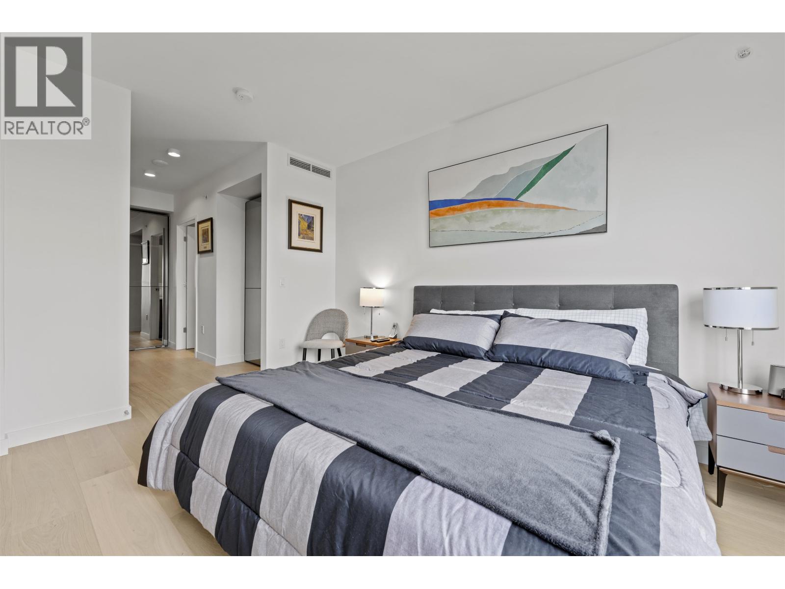 A bedroom with a large bed and a painting on the wall.