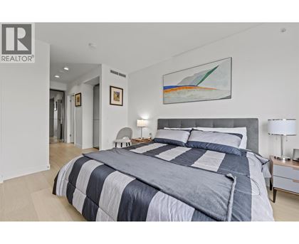 A bedroom with a large bed and a painting on the wall.