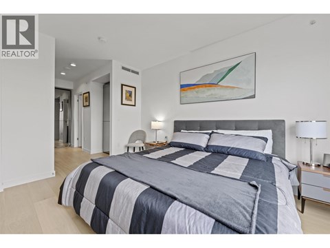 A bedroom with a large bed and a painting on the wall.