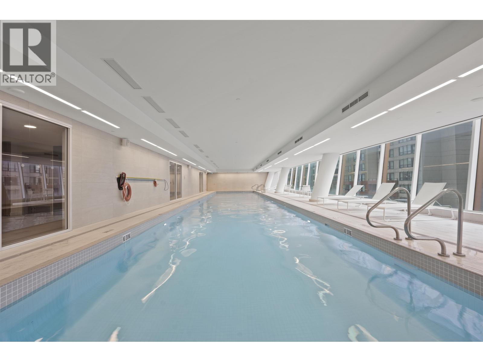 A large indoor swimming pool with a diving board.