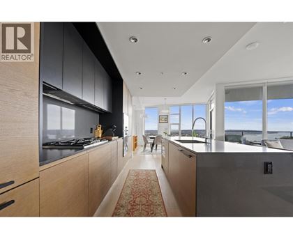 A modern kitchen with wooden cabinets and a large window overlooking the water.
