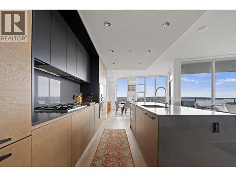 A modern kitchen with wooden cabinets and a large window overlooking the water.