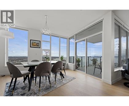 A dining room with a table and chairs with a view of the city.