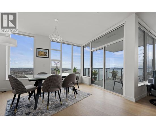 A dining room with a table and chairs with a view of the city.