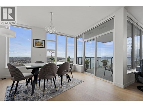 A dining room with a table and chairs with a view of the city.