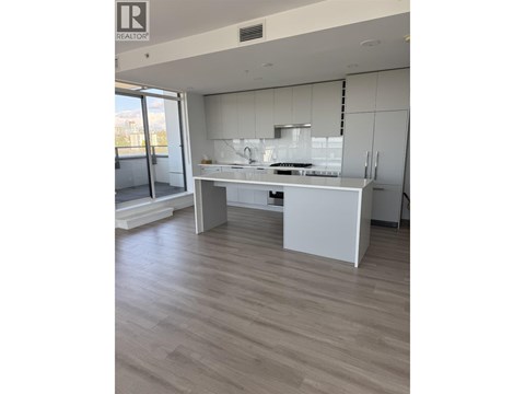 A modern kitchen with white cabinets and a wooden floor.