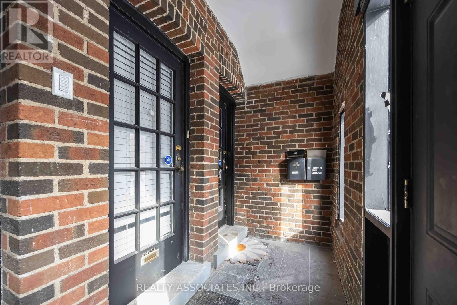 A brick wall with a door and a sign that says REALTOR.