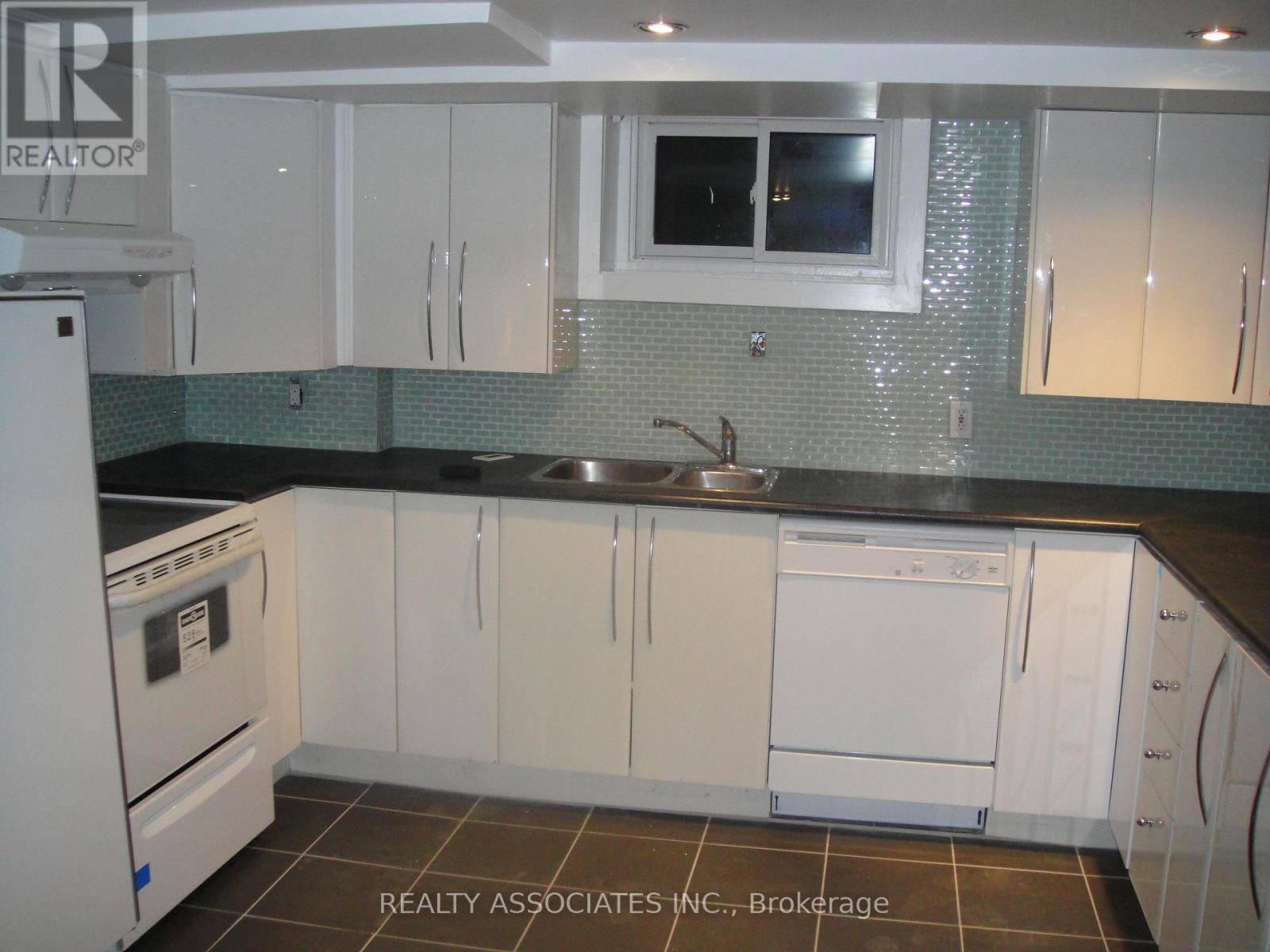 A kitchen with white cabinets and a black counter top.