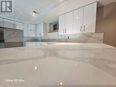 A kitchen with white cabinets and a black counter top.