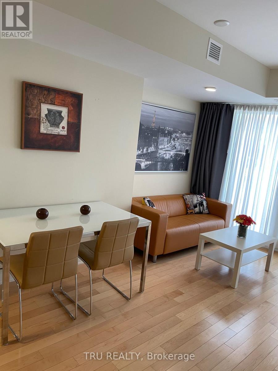 A living room with a brown couch, a white table, and a framed picture on the wall.