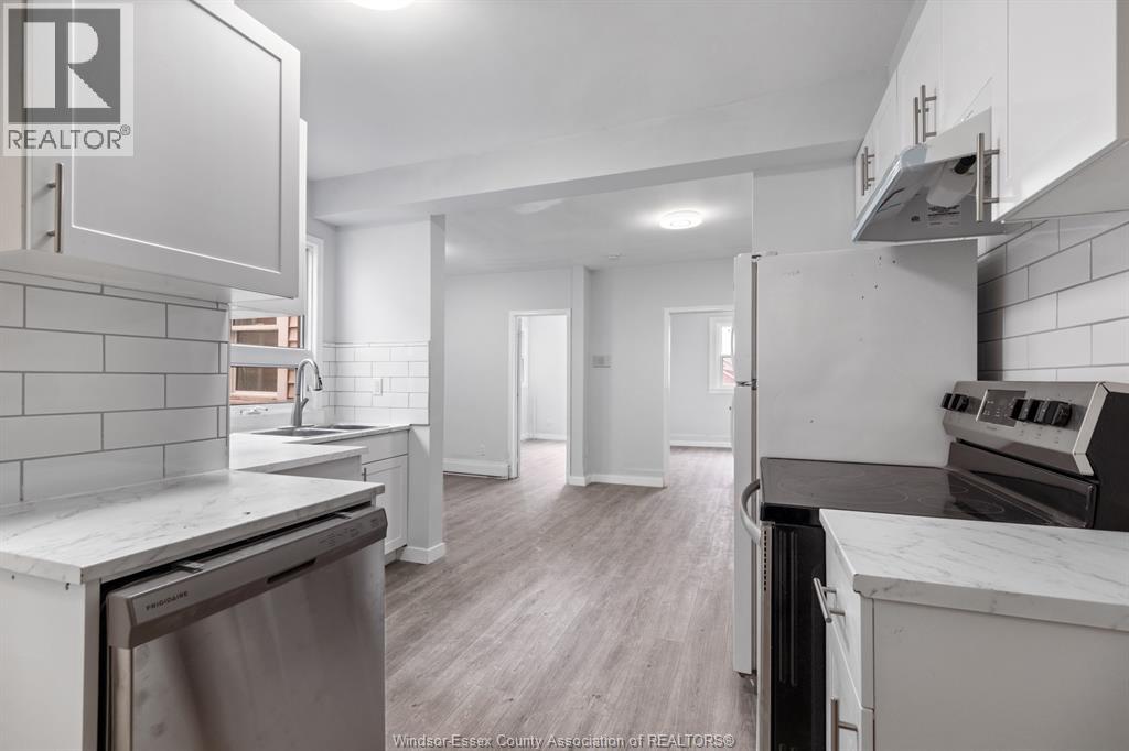 A kitchen with a stainless steel dishwasher and a white countertop.