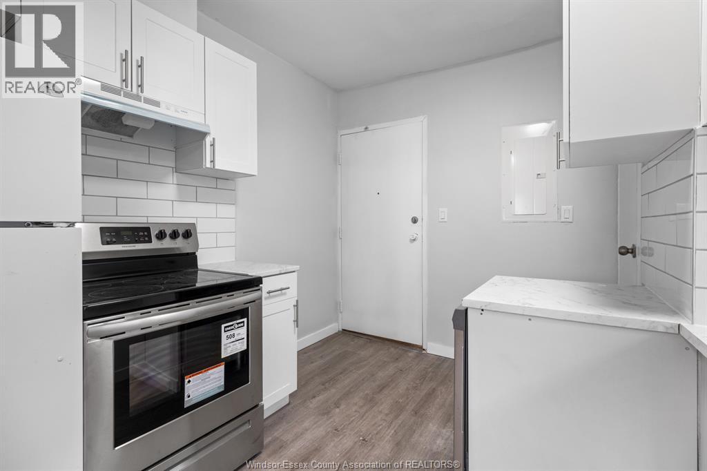 A kitchen with white cabinets and a stove top oven.