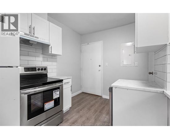 A kitchen with white cabinets and a stove top oven.