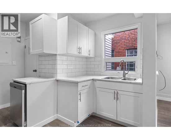 A kitchen with white cabinets and a window.