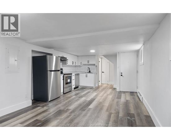 A kitchen with white cabinets and a stainless steel refrigerator.