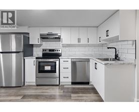 A modern kitchen with white cabinets and stainless steel appliances.