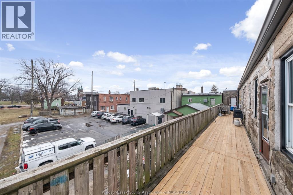 A balcony with a wooden floor overlooks a parking lot and buildings.