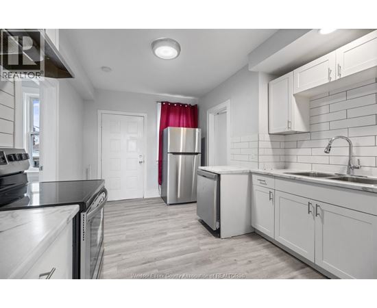 A kitchen with white cabinets and a black counter top.