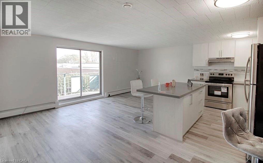 A kitchen with a refrigerator, sink, and stove.