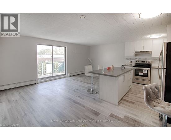 A spacious kitchen with a bar stool and a refrigerator.