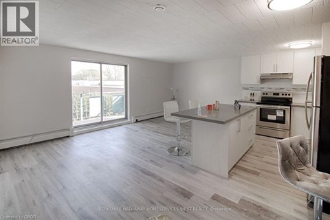 A spacious kitchen with a bar stool and a refrigerator.