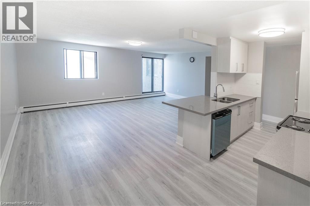 A spacious kitchen and living room with light grey flooring and white walls.