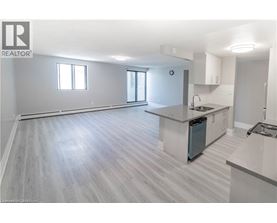 A spacious kitchen and living room with light grey flooring and white walls.