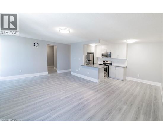 A spacious living room with a kitchenette in the background.