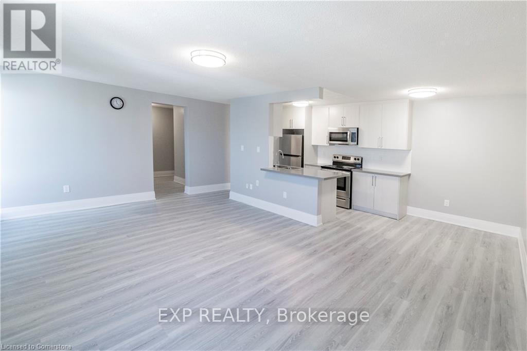 A large empty room with a kitchenette in the corner.