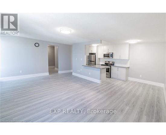 A large empty room with a kitchenette in the corner.