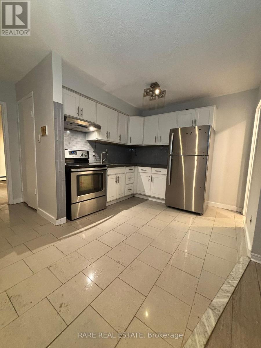 A kitchen with white cabinets and a stainless steel refrigerator.