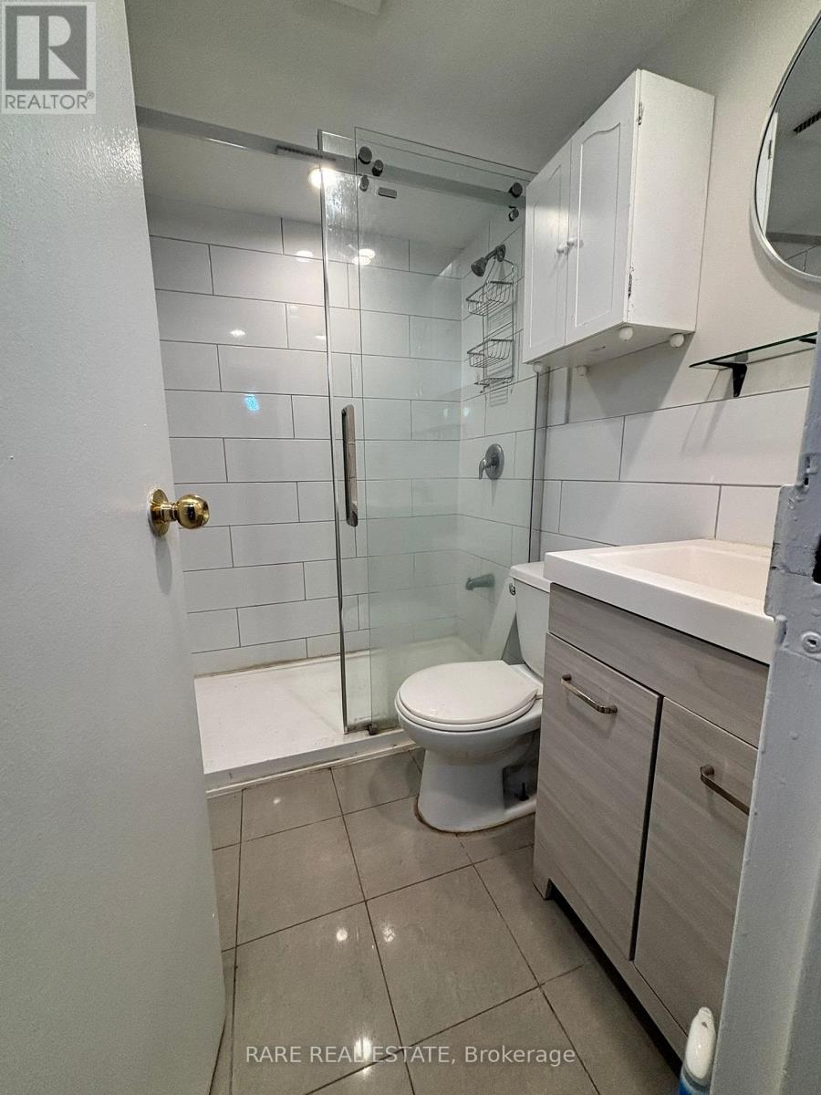 A small white bathroom with a toilet, sink, and shower.