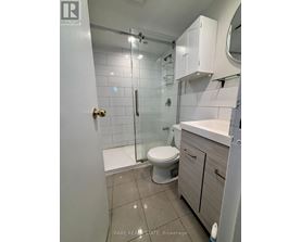 A small white bathroom with a toilet, sink, and shower.