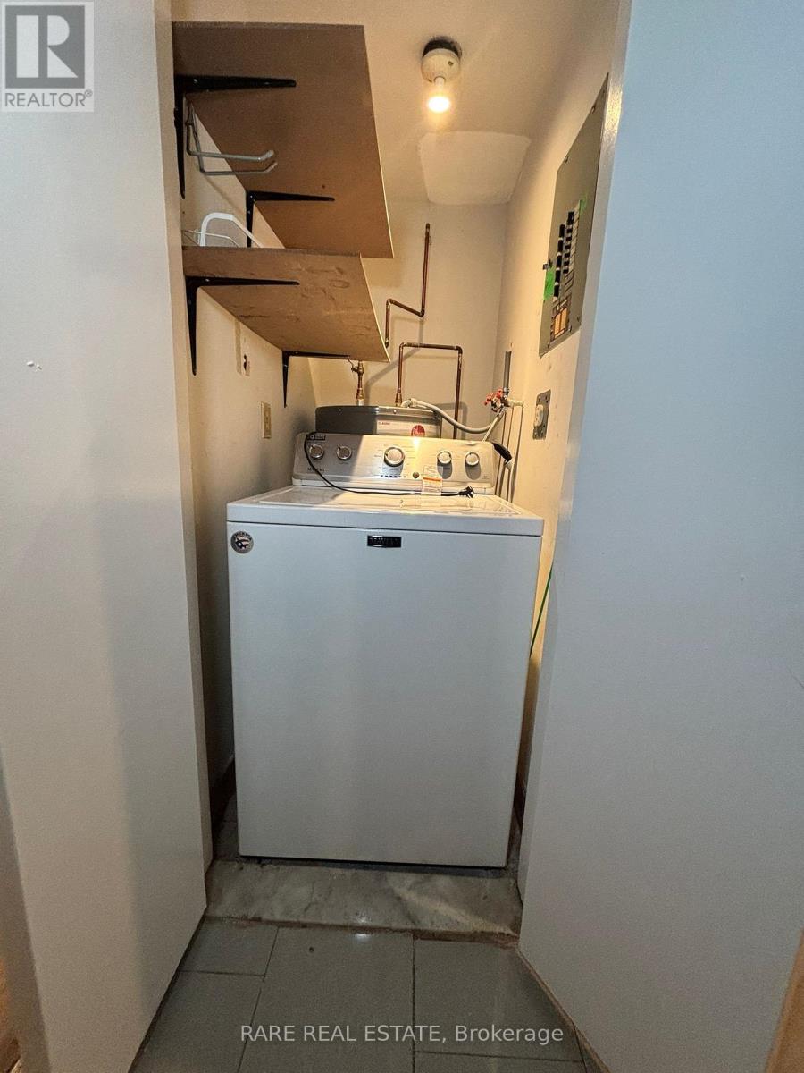 A small white refrigerator in a narrow hallway.