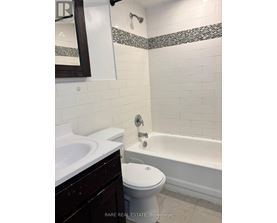 A white toilet sits next to a bathtub in a bathroom.