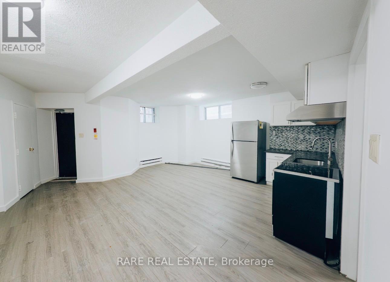 A spacious, empty room with a kitchenette and a dining area.
